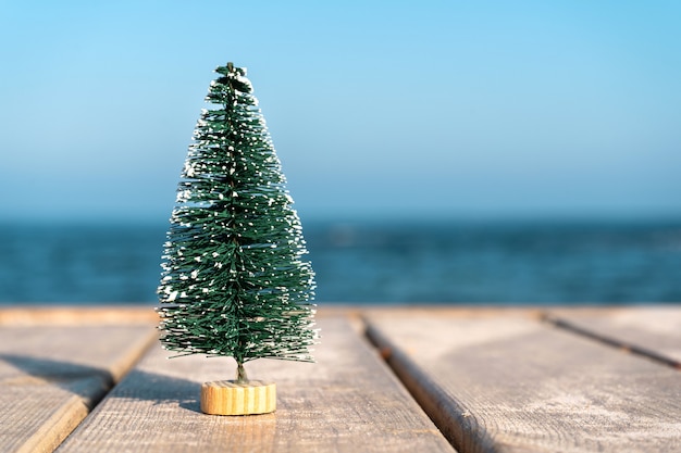 Petit sapin de Noël sur une jetée en bois au bord de la mer Copy space