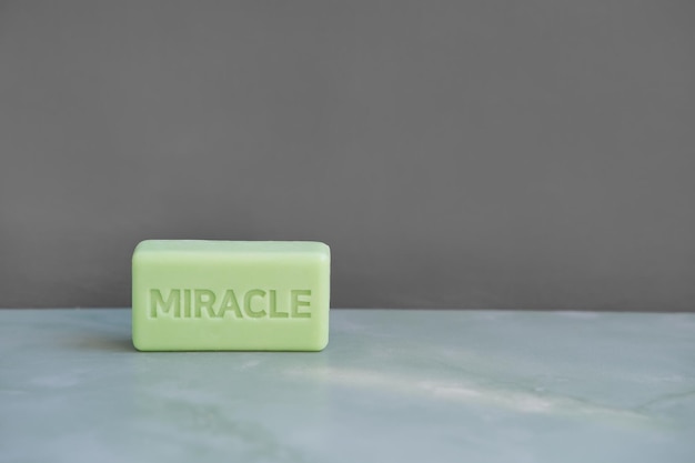 petit savon vert avec inscription miracle contre mur gris