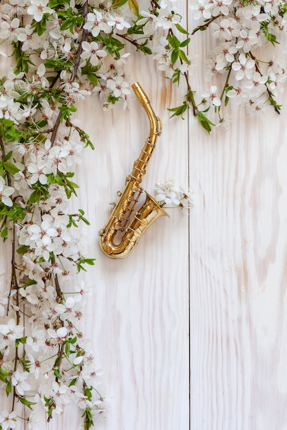 Petit saxophone doré et branches de cerisier en fleurs.