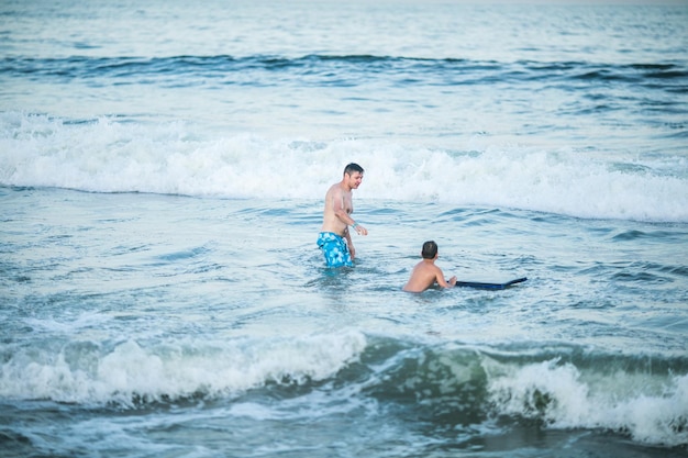 Un petit surfeur apprend à monter sur une planche de surf sur une vague de mer