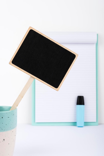 Petit tableau noir avec un message important dans une tasse sur un bureau avec un presse-papiers et un marqueur Petit tableau avec des informations cruciales sur une table avec du papier Idées actuelles présentées