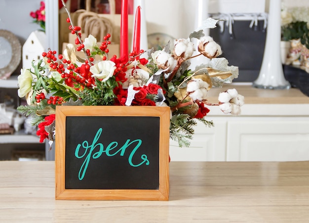 Petit tableau avec texte OUVERT à l'intérieur d'un magasin de fleurs pendant la saison des vacances de Noël