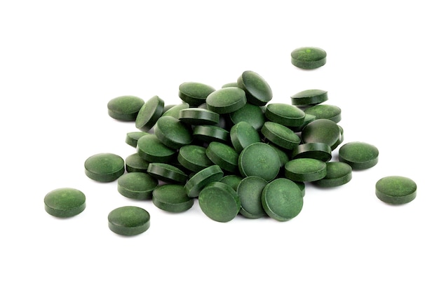 Un petit tas de pilules de spiruline verte isolé sur fond blanc