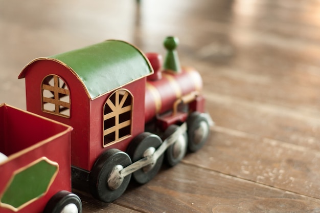 Photo un petit train en bois rouge avec un toit vert et des roues noires sur un fond en bois usé