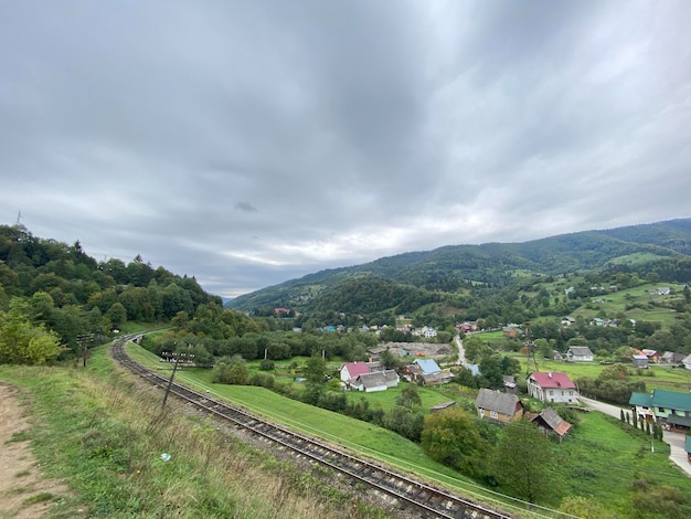 Un petit village dans les montagnes Forêt roches nuages Beau paysage Europe Maisons traditionnelles en bois et un chemin de fer