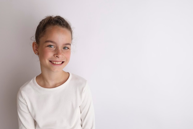 Petite adolescente émotive en chemise blanche 11 12 ans sur un fond blanc isolé Portrait en studio pour enfants Placez le texte pour copier l'espace pour l'inscription annonçant les produits pour enfants