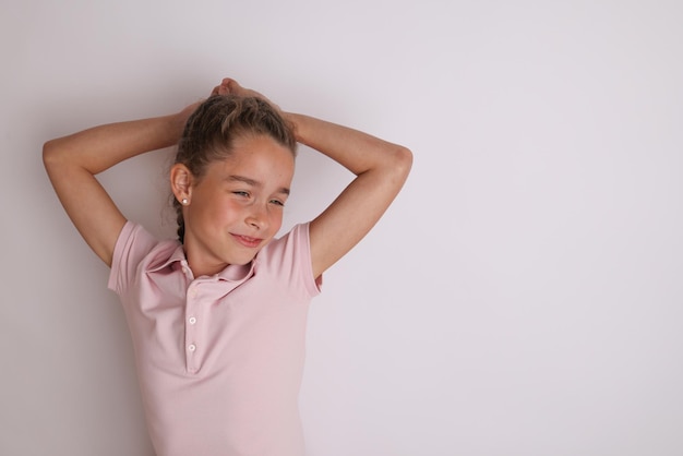 Petite adolescente émotive en chemise rose 11 12 ans sur un fond blanc isolé Portrait en studio pour enfants Placez le texte pour copier l'espace pour l'inscription annonçant les produits pour enfants