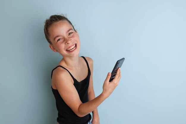 Petite adolescente émotive en chemise rose 11 12 ans sur un fond bleu isolé avec une tablette dans ses mains Portrait en studio pour enfants Placez le texte pour copier l'emplacement de l'inscription