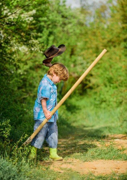 Petite aide travaillant dans le jardin. Enfant mignon dans la nature s'amusant avec une pelle. Je veux trouver des trésors. Enfance heureuse. Aventure chasse aux trésors. Petit garçon avec une pelle à la recherche de trésors.