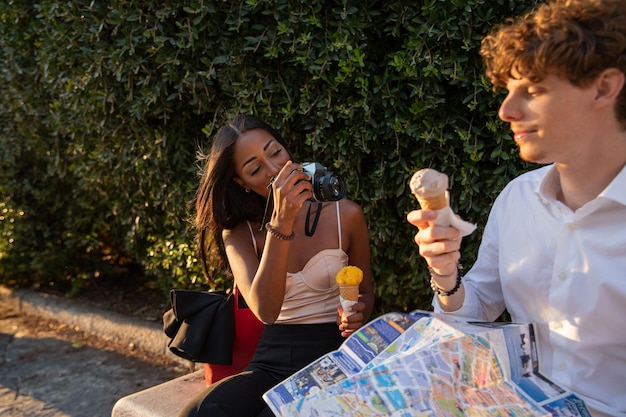 Petite amie prend des photos de son petit ami avec l'appareil photo analogique pendant qu'ils mangent de la glace et sont en vacances