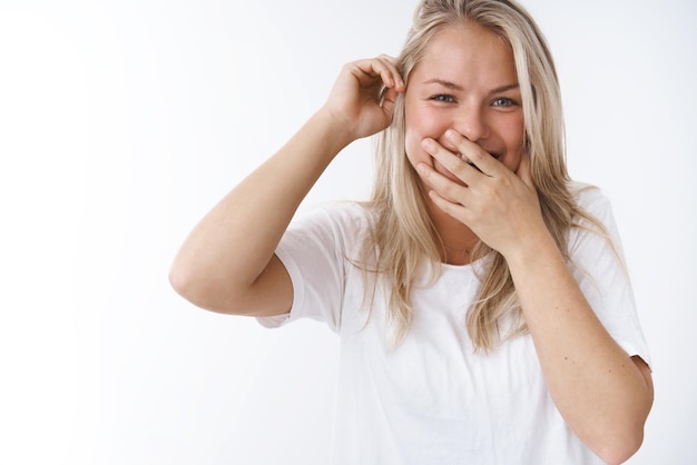 Petite amie riant sur petit ami drôle maladroit gloussant et souriant bouche coning palm mettre mèche de cheveux derrière l'oreille en regardant l'appareil photo heureux