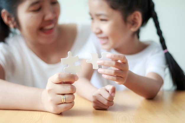 Petite asiat jouant puzzle avec sa mère pour le concept de famille peu profonde