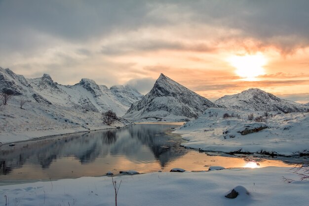 Petite baie du fjord norvégien entourée de montagnes enneigées.