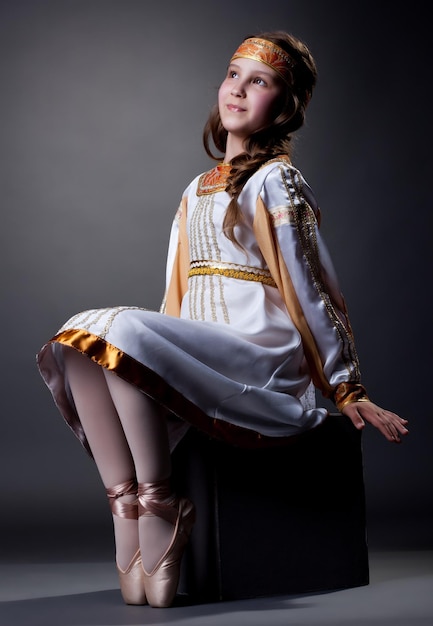 Une petite ballerine rêveuse posant dans une robe folklorique
