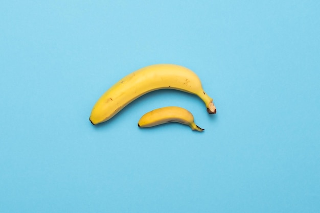 Petite banane comparer la taille avec la banane sur le concept de pénis de taille de fond bleu