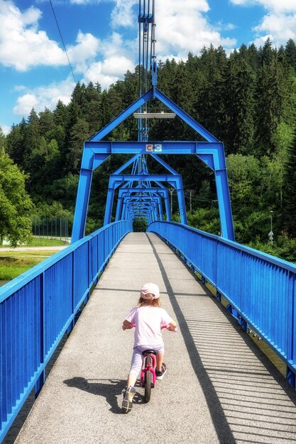 Petite bébé qui fait du vélo sur le pont pour les piétons