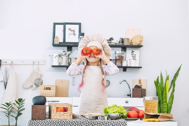 Petite belle enfant fille cuisiner dans la cuisine avec différents légumes et spaghettis