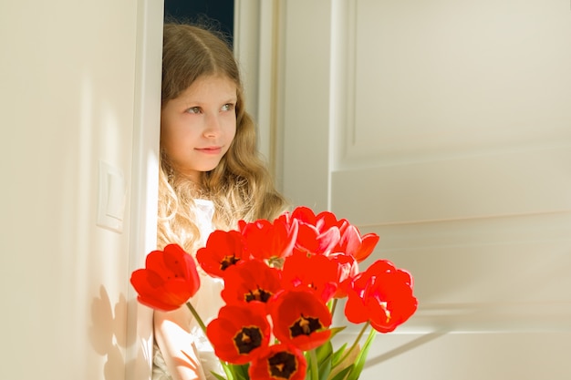 Petite belle fille avec bouquet de tulipes rouges, présente pour la mère, fête des pères