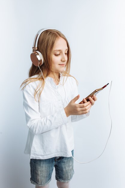 Petite belle fille, écouter de la musique et regarder le téléphone