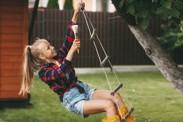 Petite belle fille avec un pinceau sur une balançoire