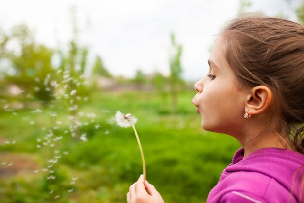 Petite belle fille tient le pissenlit de printemps dans sa main