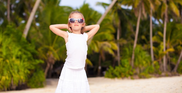Petite belle fille vêtue d'une robe longue sur une plage tropicale