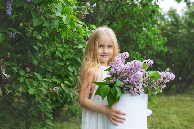 Petite et belle petite fille mignonne et heureuse avec des fleurs lilas dans ses mains dans la nature