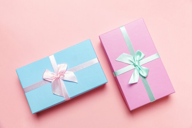 Petite boîte cadeau enveloppé de papier rose et bleu isolé sur rose pastel coloré tendance