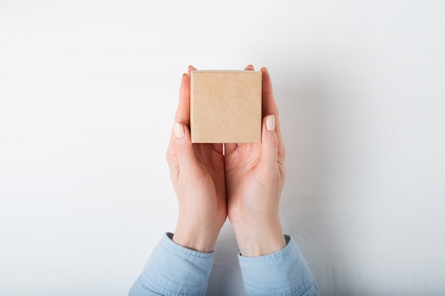 Petite boîte en carton carrée dans des mains féminines.