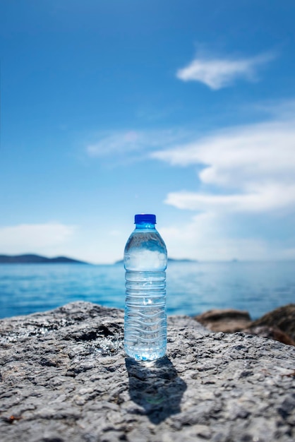 Petite bouteille d'eau minérale sur des rochers au bord de la mer