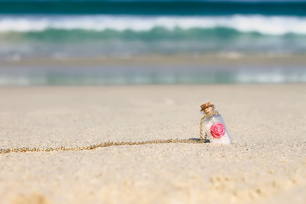 Petite bouteille souvenir en sable blanc sur la mer turquoise