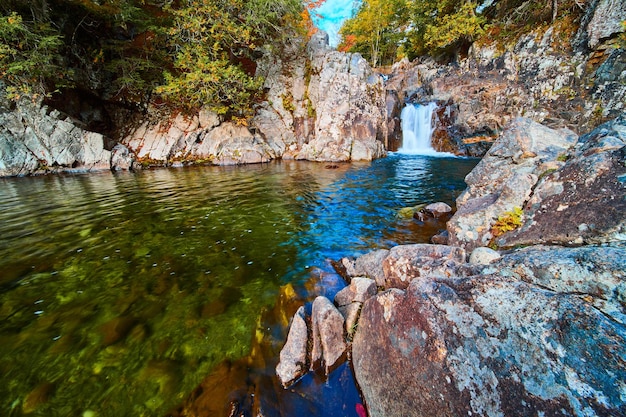 Petite cascade sur des rochers dans une rivière bleue et verte à côté d'énormes rochers dans la forêt