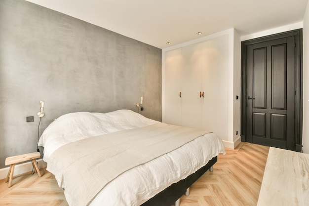 Une petite chambre avec un grand lit blanc et une armoire dans une maison confortable