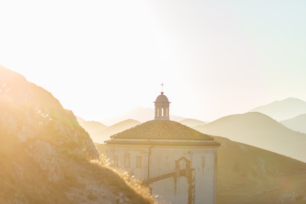 La petite chapelle octogonale près des ruines du château de Rocca Calascio au coucher du soleil en contre-jour, point de repère dans le Parc National du Gran Sasso, Abruzzes, Italie. Fond pittoresque de montagnes.