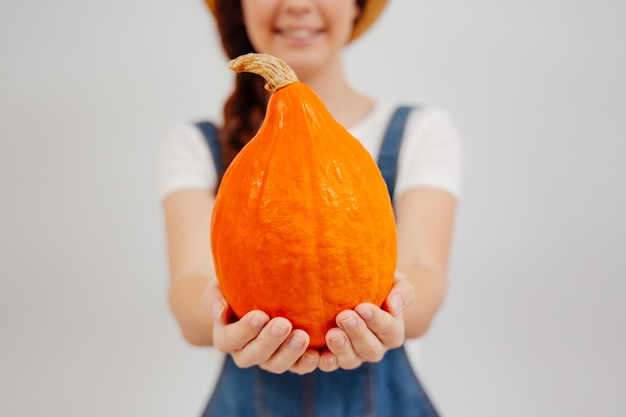 Petite citrouille orange de la récolte d'automne entre les mains d'un agriculteur flou