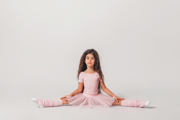 Photo petite danseuse de ballerine basanée dans un étudiant de l'académie de tutu rose posant sur fond blanc