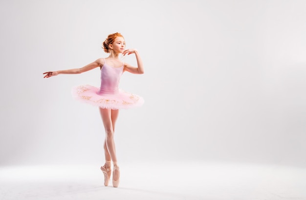 Petite danseuse de ballerine dans un étudiant de l'académie de tutu rose posant sur fond blanc