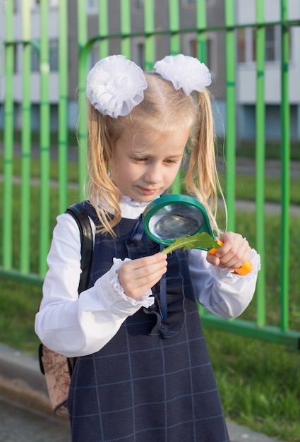 La petite écolière examine l'usine par la loupe