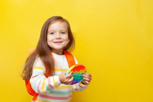 Une petite écolière heureuse tient un pop dans ses mains Fond jaune