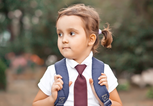 Petite écolière mignonne en uniforme avec sac à dos cartable