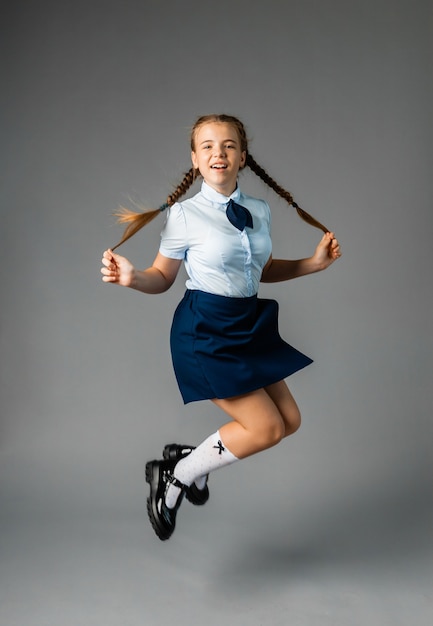 Petite écolière avec un sourire heureux. Petite écolière en uniforme scolaire. Écolière mignonne aux cheveux longs. Enseignement primaire. Écolière parfaite