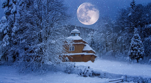 Petite église en bois. La veille de Noël pendant les chutes de neige, l'architecture populaire ancienne. Fond d'écran avec l'ambiance du Nouvel An