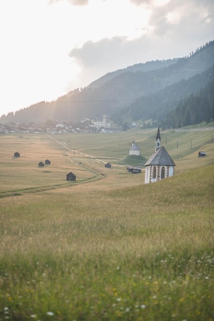 Photo une petite église dans un champ avec un fond de montagne