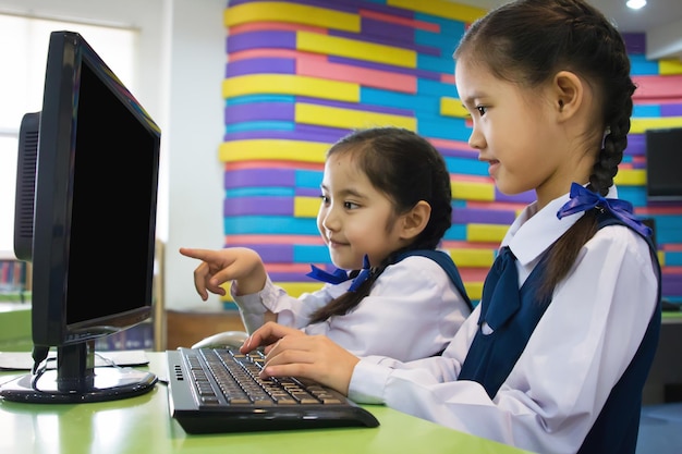 Photo petite étudiante asiatique mignonne utilisant un ordinateur à l'école avec un écran vide