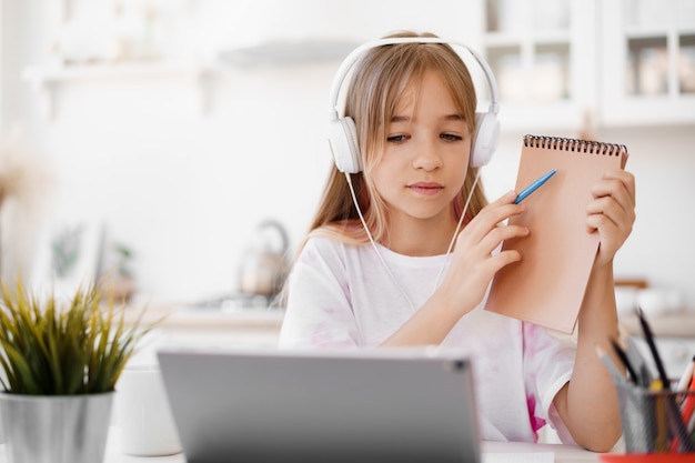 Petite étudiante à domicile ayant des cours en ligne à l'aide d'une tablette numérique