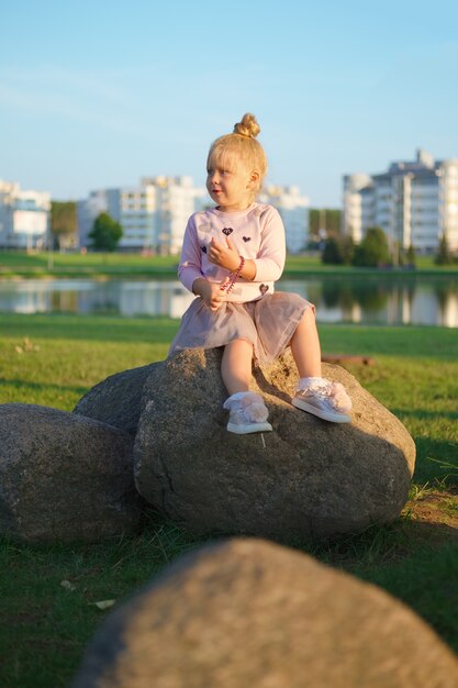 Petite femme assise sur la pierre au coucher du soleil