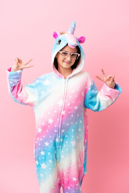 Petite femme caucasienne portant un pyjama licorne isolé sur fond rose