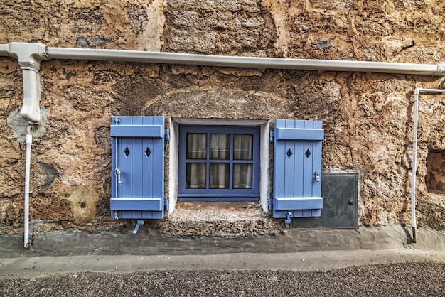 Petite fenêtre lilas dans un mur rustique