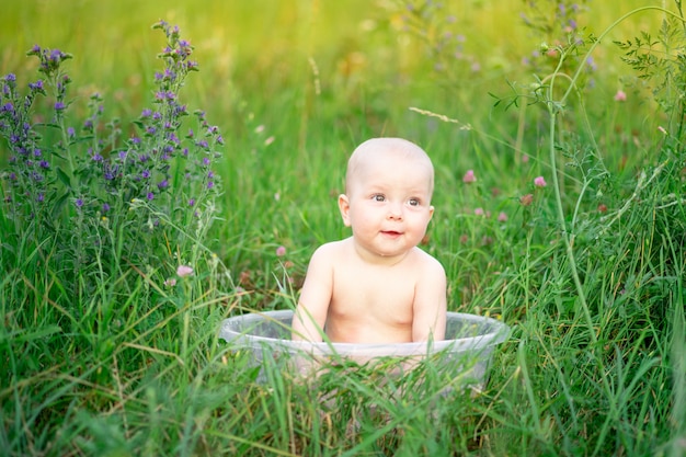 Petite fille de 10 mois se baigne dans un bassin dans l'herbe en été