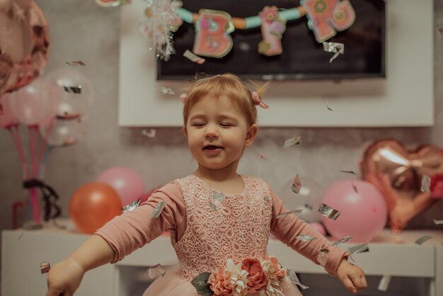 Petite fille de 2 ans en robe rose avec son premier gâteau d'anniversaire, carte de joyeux anniversaire, une jolie petite fille fête son premier anniversaire entourée de cadeaux